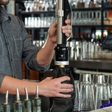 A bartender uses a Coravin wine tool to pour wine from a bottle while keeping it sealed and fresh.