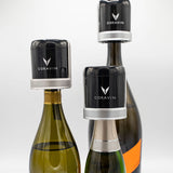 Three wine bottles with Coravin wine preservation devices on top, featuring the Coravin logo prominently displayed.