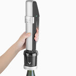 Hand holding a Coravin wine preservation system over a bottle, demonstrating how to use it for serving wine.