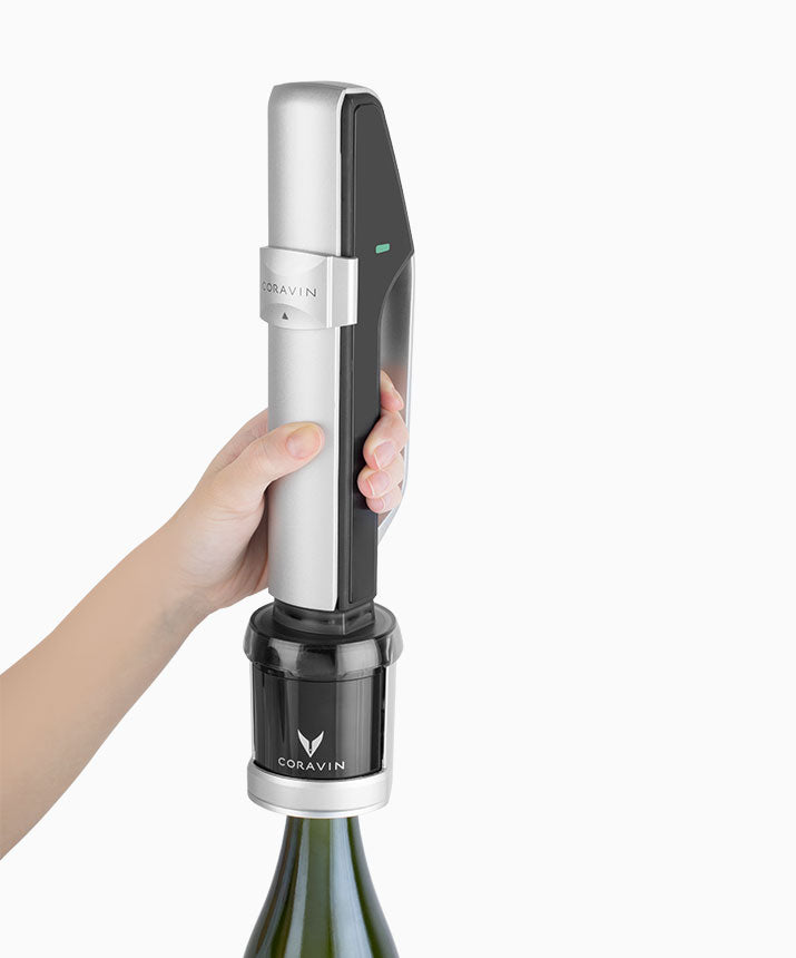 Hand holding a Coravin wine preservation system over a bottle, demonstrating how to use it for serving wine.