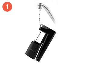 Black water filtration device attached to a faucet, with water flowing from the spout.