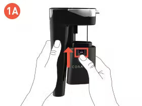 Hands holding a black soda maker, with an arrow pointing to a button labeled with a red square.