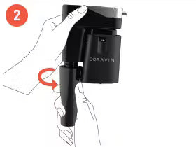 Hand holding a Coravin wine opener, demonstrating a rotating action to engage the device, step 2 of the instructions.