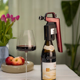 A Coravin wine opener perched on a bottle of 2015 Ex Voto Hermitage, next to a glass of red wine and fresh apples.