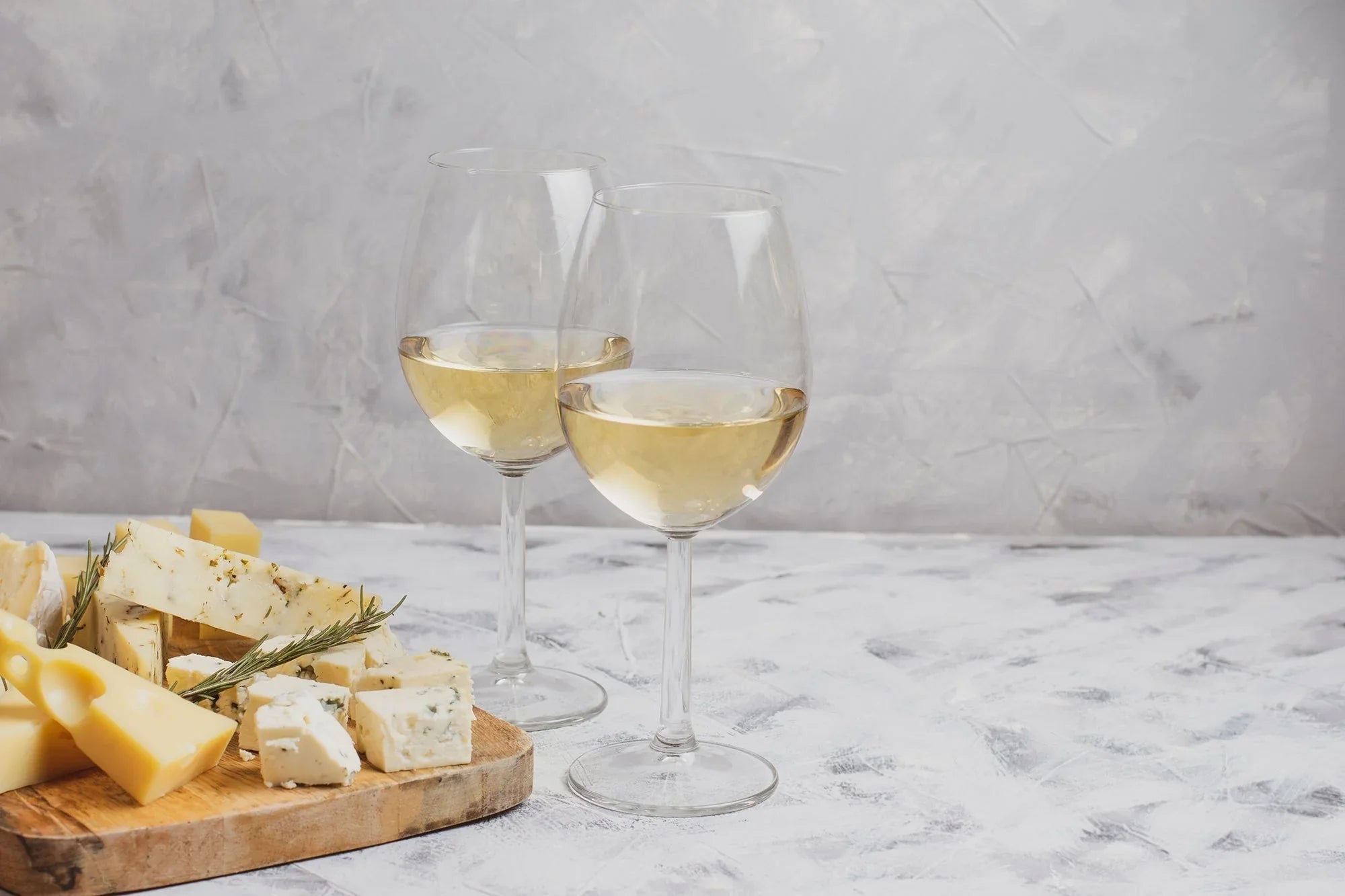 two glasses of dry white wine with cheese board