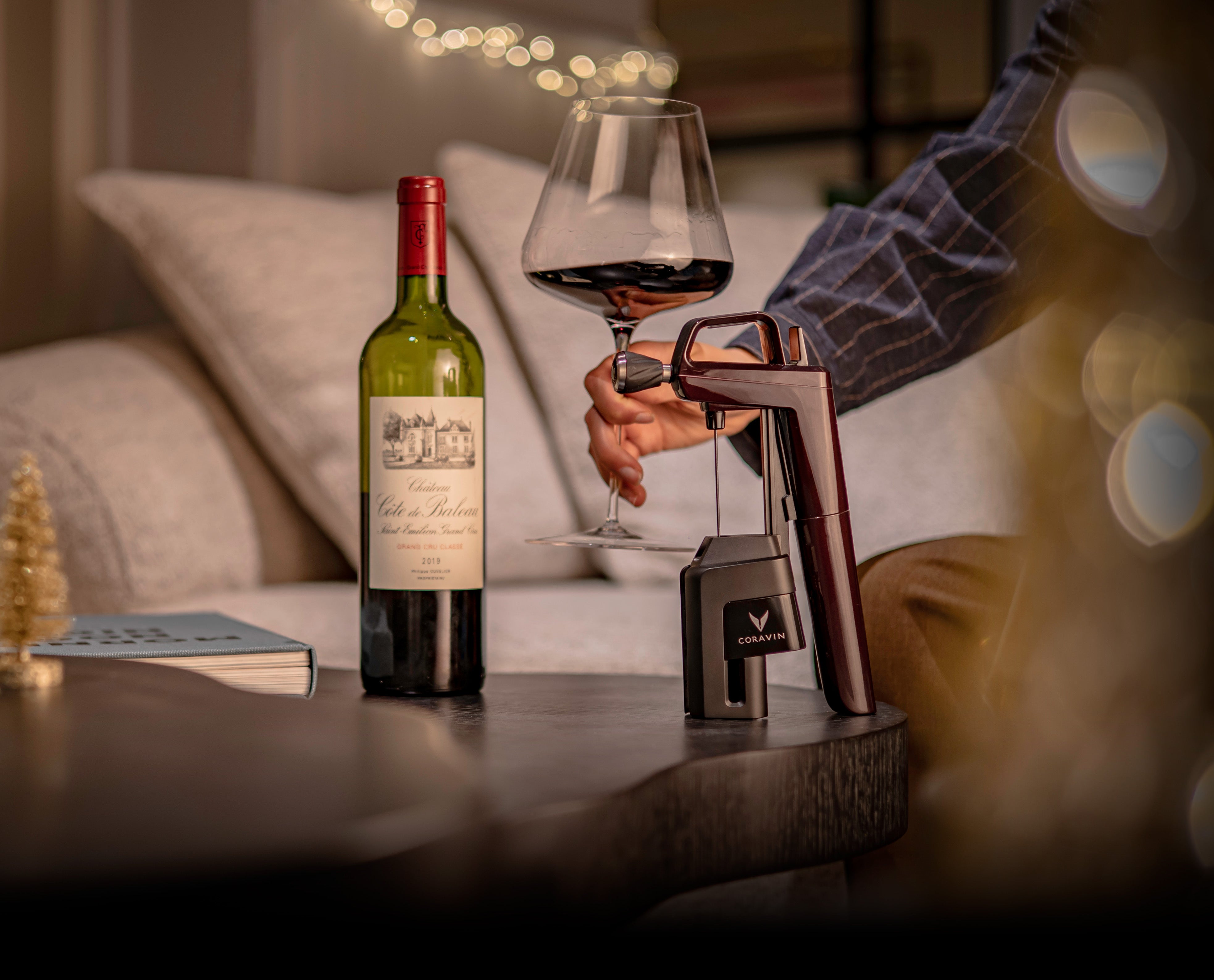 Wine bottle and glass with a wine dispenser on a table, blurred background