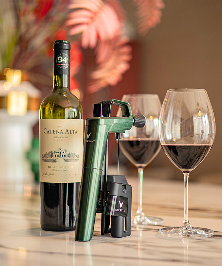 2020 Catena Alta Malbec wine bottle, Coravin wine preservation system, and two glasses of red wine on a marble surface.